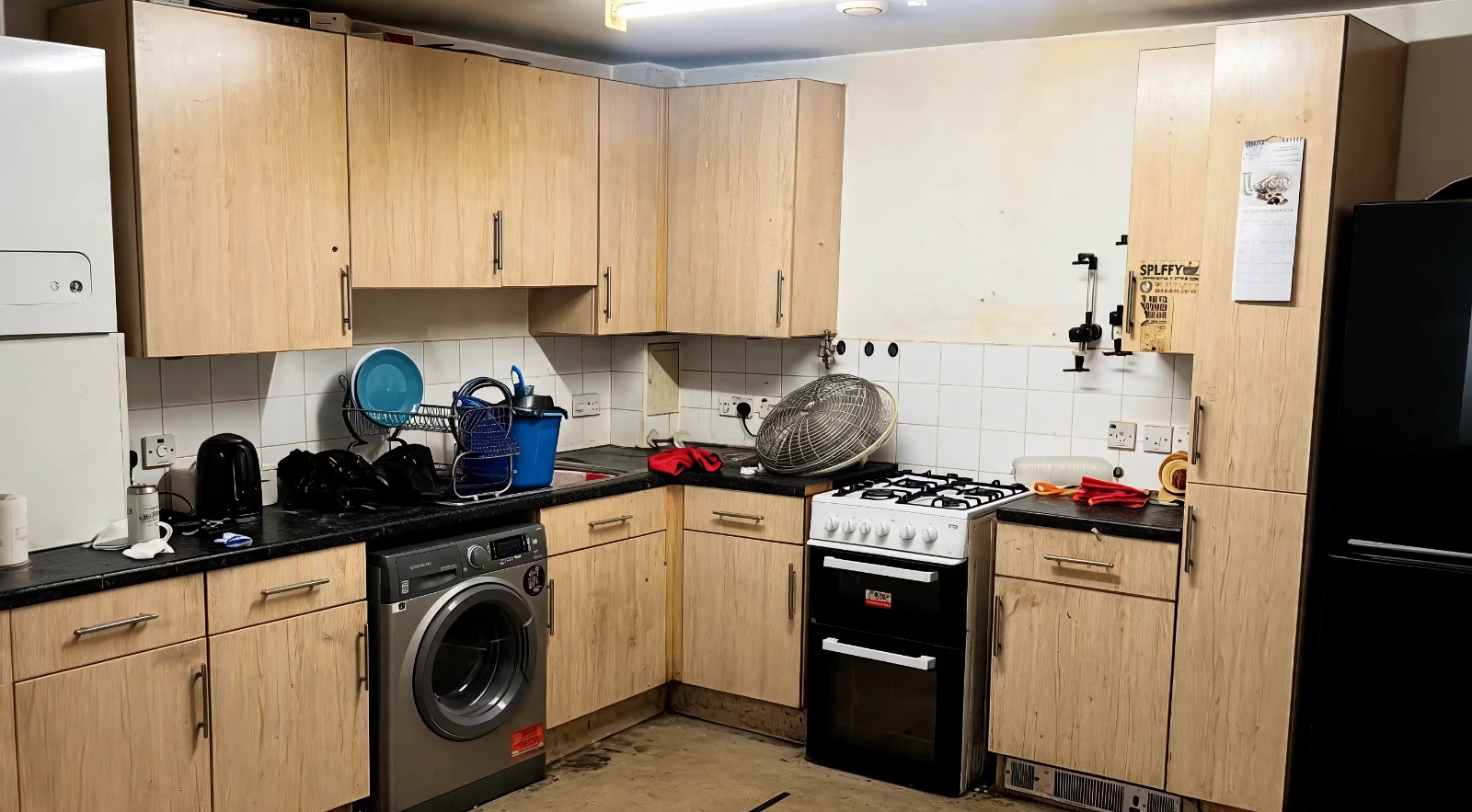 A U-shaped kitchen in matt blue handleless units with marble-effect worktops and a full-height stone splashback