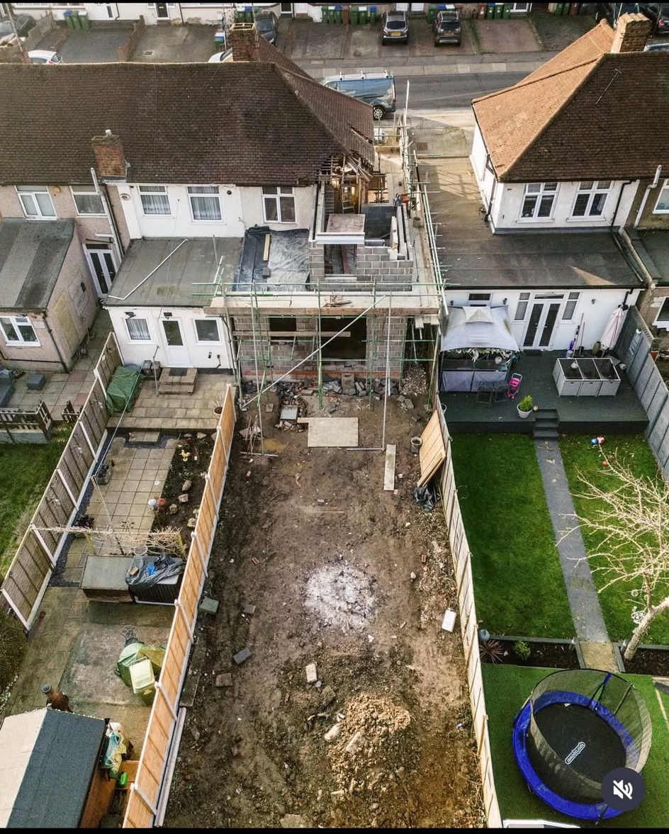 Aerial view of a rear and side extension under construction in blockwork, with scaffolding and a cleared garden behind a terrace