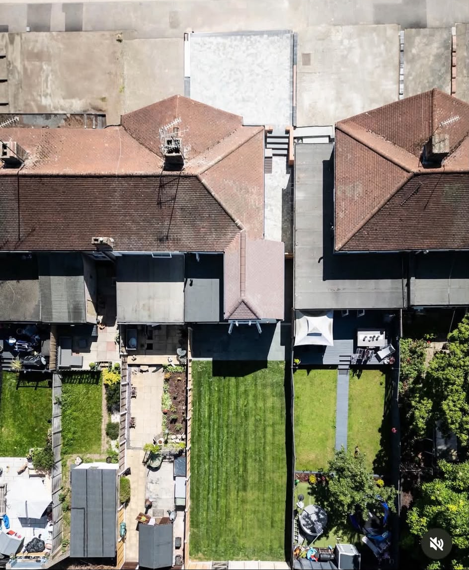 Top-down aerial view of a terrace roof with a new hipped side extension roof and a flat rear extension roof above a striped lawn